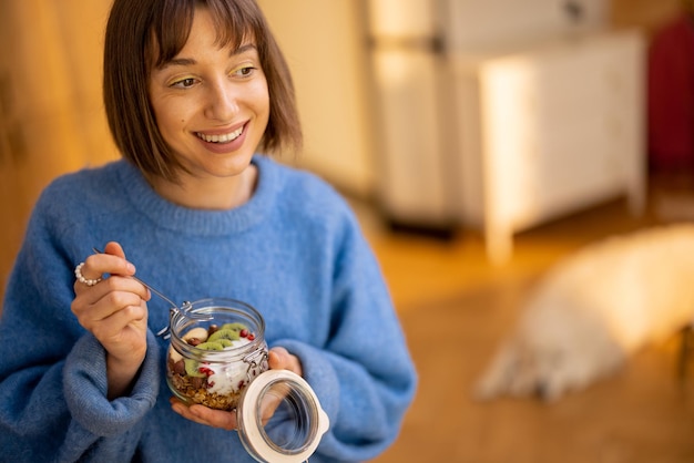 Frau genießt Granola-Frühstück in Schüssel zu Hause