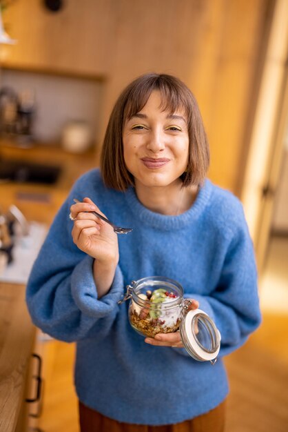 Frau genießt Granola-Frühstück in Schüssel zu Hause