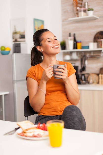 Frau genießt ihre Freizeit und trinkt morgens eine Tasse Kaffee in der Küche