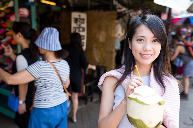 Frau genießt Kokosnussgetränk auf dem Wochenendmarkt