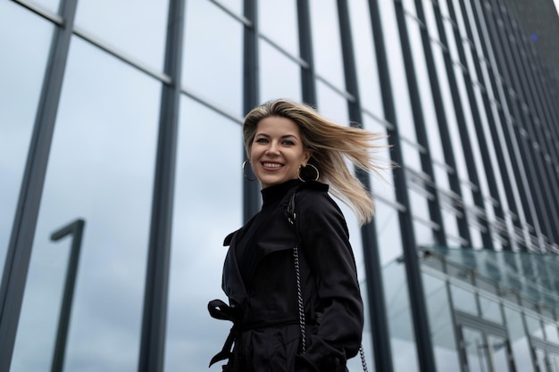 Frau Geschäftsfrau mit fliegenden Haaren im Wind vor dem Hintergrund eines Bürogebäudes