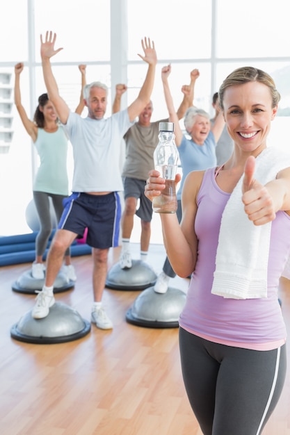 Frau Gestikulieren Daumen hoch mit Menschen, die Hände Fitness Studio ausdehnen