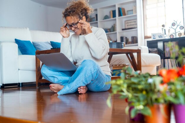 Frau glücklicher Unternehmer und kleines Online-Geschäftsmanagement-Konzept Lebensstil Eine Frau mittleren Alters, die zu Hause sitzt, an einem Laptop arbeitet, Computer und drahtlose Verbindung allein in Innenräumen benutzt