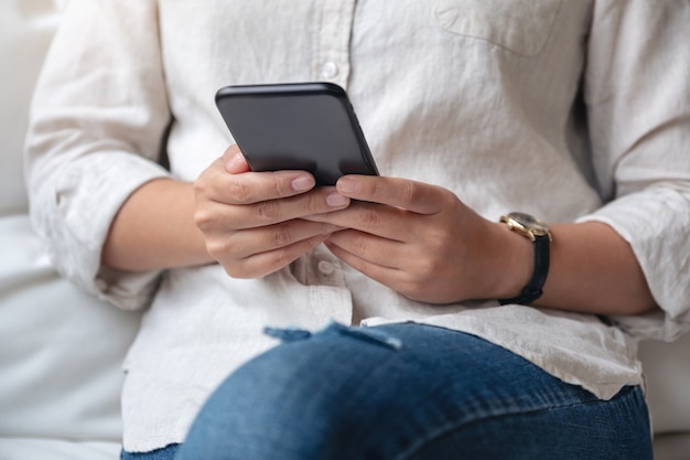 Frau hält, benutzt und betrachtet Smartphone im Café