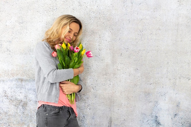 Foto frau hält blumen an der wand