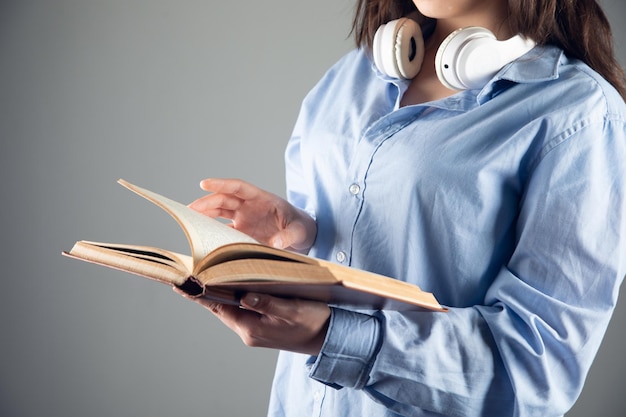 Frau hält Buch und Kopfhörer Hörbuchkonzept