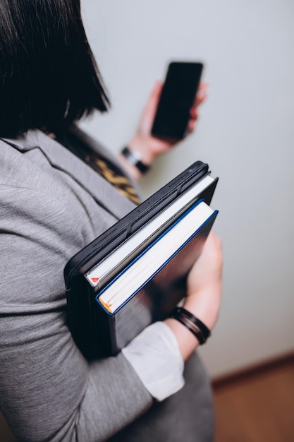 Frau hält Dokumente, ein Notizbuch und ein Tablet in der Hand, ein Telefon in der zweiten Hand ohne Gesicht