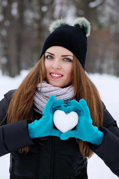 Frau hält ein Herz aus Schnee. Das Konzept des Valentinstags
