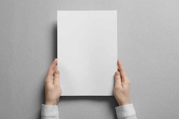 Frau hält ein leeres Blatt Papier auf hellem Hintergrund Mock up für Design