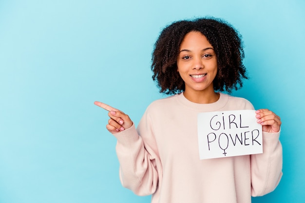 Frau hält ein Mädchen Power Plakat lächelnd und zeigt zur Seite