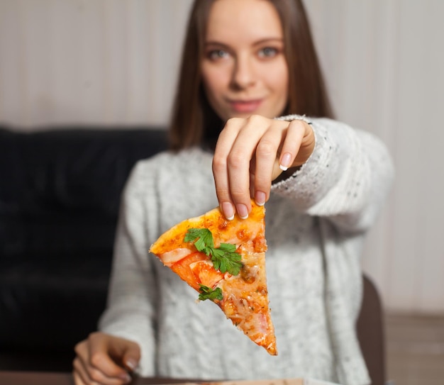 Frau hält ein Stück Pizza in der Hand