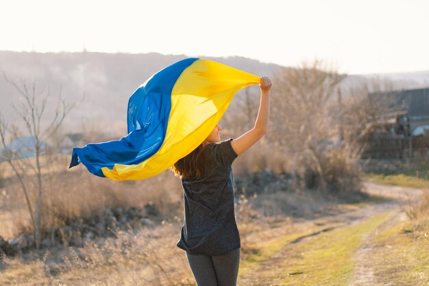 Frau hält eine gelb-blaue Flagge der Ukraine im Freien