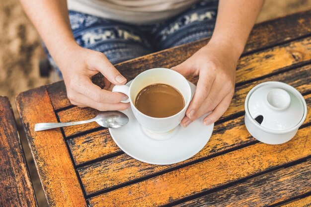 Frau hält eine Tasse Kaffee in einem Straßencafé