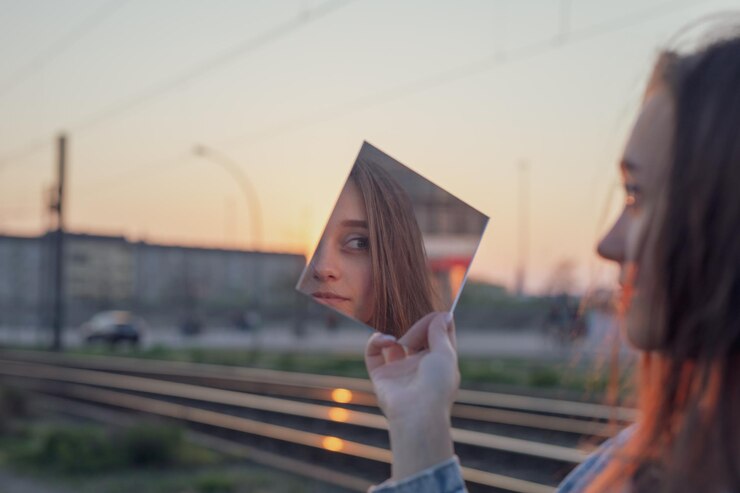 Foto frau hält einen spiegel gegen den himmel bei sonnenuntergang