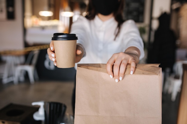 Frau hält Einweg-Craft-Tasse Kaffee und Verpackung mit Lebensmittel-Taka-Away-Konzeptplatz für Text