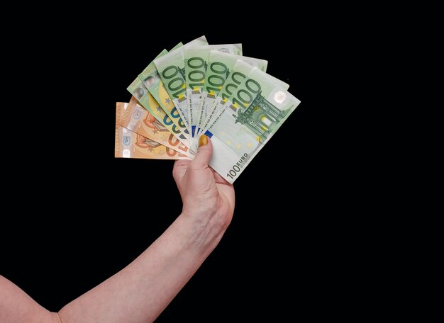 Frau hält Euro-Bargeld in der Hand auf schwarzem Hintergrund