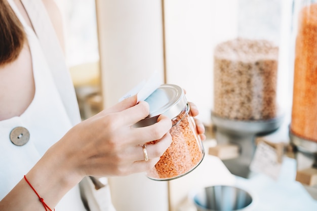 Foto frau hält glas mit roten linsen in plastikfreiem lebensmittelgeschäft mädchen kauft in zero waste shop