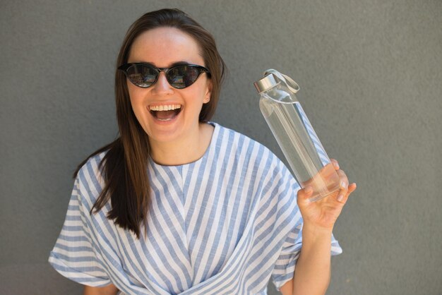 Frau hält Glasflasche mit klarem Wasser