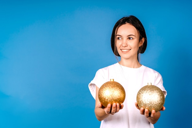 Frau hält große Weihnachtskugeln an der blauen Wand