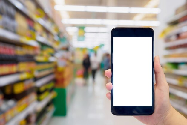 Frau hält Handy beim Einkaufen im Supermarkt