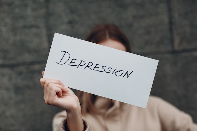 Frau hält in der Hand Blatt Papier mit Wort Depression