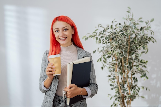 Frau hält Kaffee in Einweg-Aktentasche zum Mitnehmen mit Dokumentenschlüsseln zur Wohnung