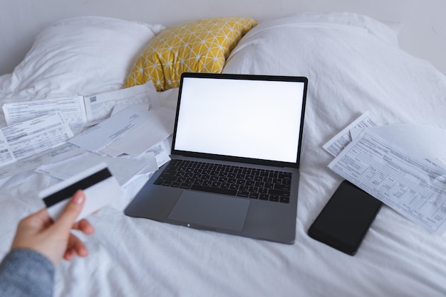 Frau hält Karte in der Hand Laptop mit weißem Bildschirm auf dem Bett im Hintergrund