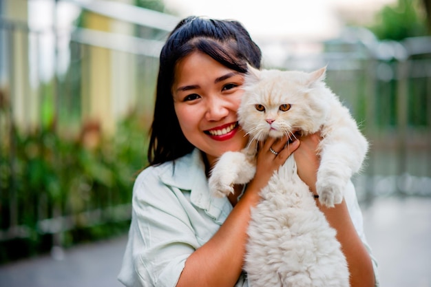 Frau hält Katze und spielt zu Hause mit Liebe zu Katzen. Das Lächeln glitzert in seiner Verbundenheit mit seiner flauschigen Haustierkatze. Die Beziehung zwischen Menschen und Katzen. Katzenbesitzer, Hauskatzen, dicke Katzen