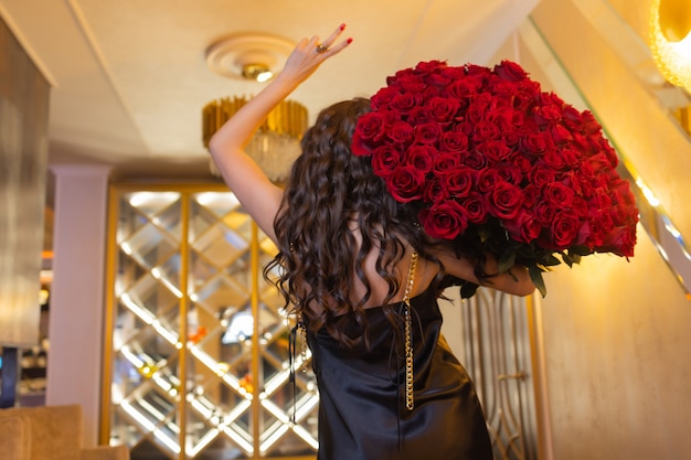 Frau hält Luxusblumenstrauß aus roten Rosen.