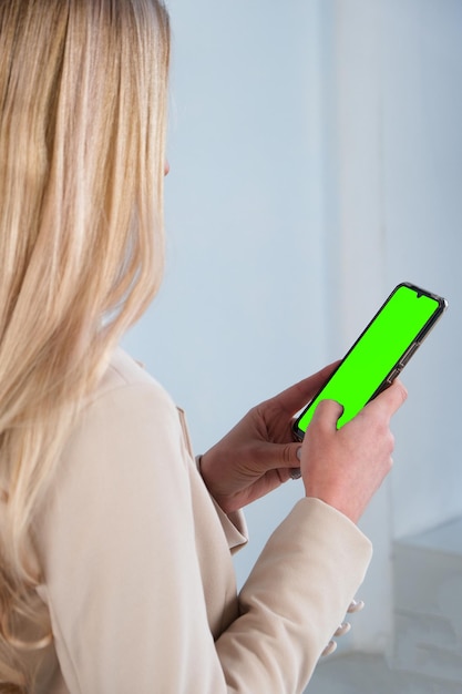 Frau hält Smartphone-Attrappe mit grünem Bildschirm in der Hand, überprüft Social Media, bestellt Essenslieferungen oder macht Online-Shopping Mobile Technologie und Kundenkonzept