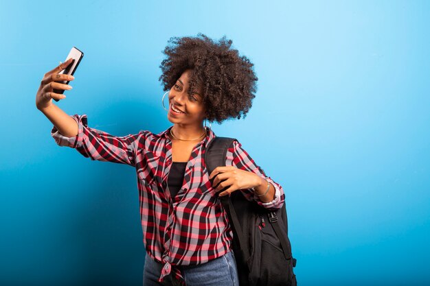 Frau hält Smartphone, das Selfie-Foto auf dem blauen Hintergrund nimmt