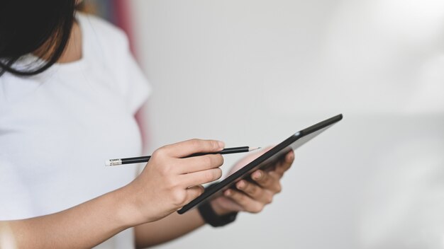 Frau hält Tablette und Bleistift.