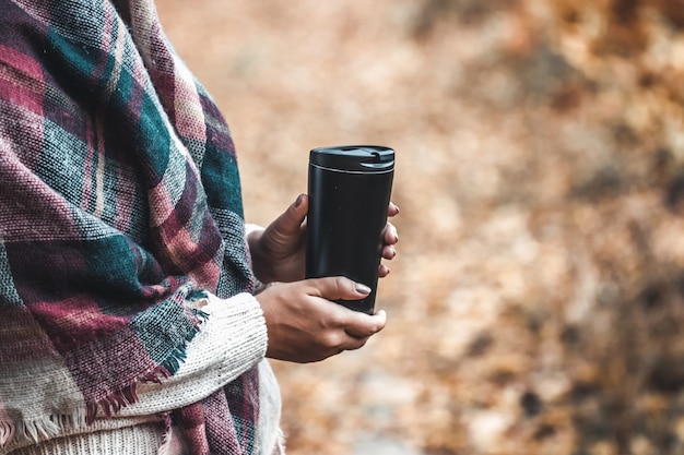 Frau hält Tasse im Wald