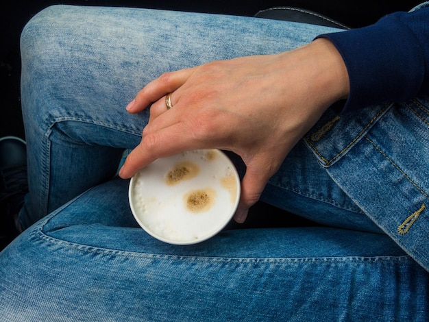 Frau hält Tasse Kaffee im Inneren des Autos Reiselebensstil Beine in Jeans