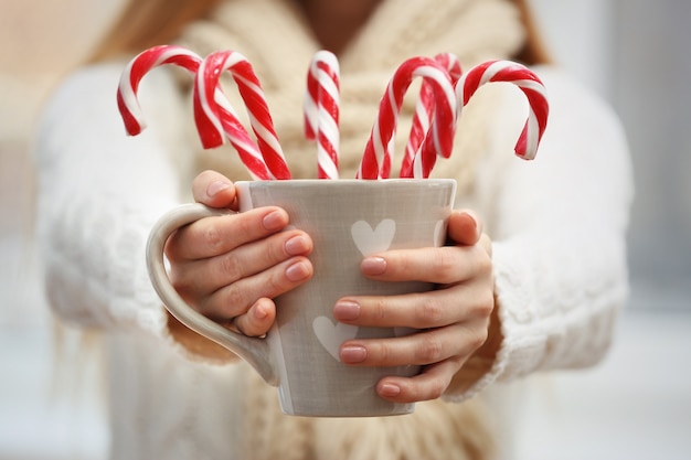 Foto frau hält tasse mit zuckerstangen, nahaufnahme