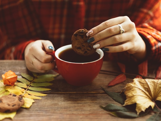 Frau hält Tasse warmen Tee und Keks an der herbstlichen Wand. Freuden des Herbstes. Krankheitsprävention