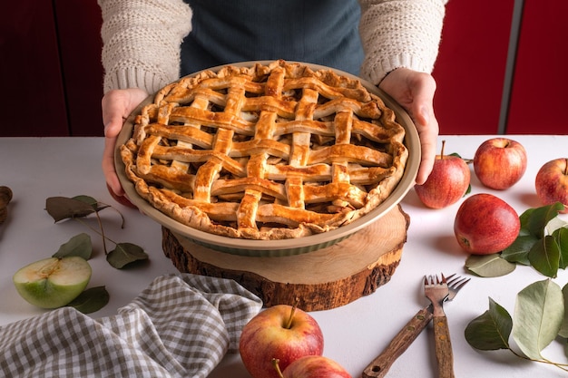 Frau hält und zeigt leckeren gekochten Apfelkuchen, der bereit ist, die klassische Thanksgiving-Torte zu essen