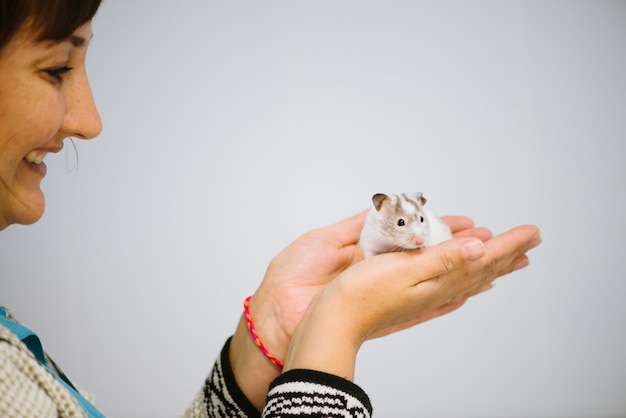 Frau hält weiße pelzige kleine Maus.