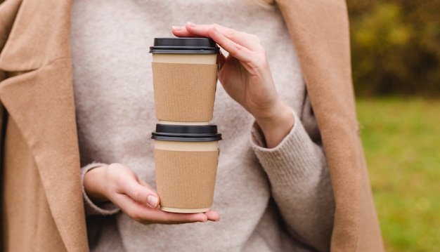 Frau hält zwei Papierkaffeetassen
