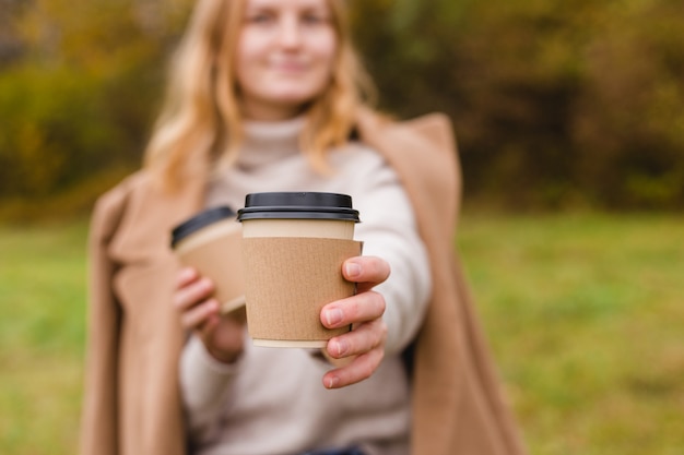 Frau hält zwei Papierkaffeetassen