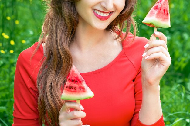 Frau hält zwei Stücke Wassermelone.