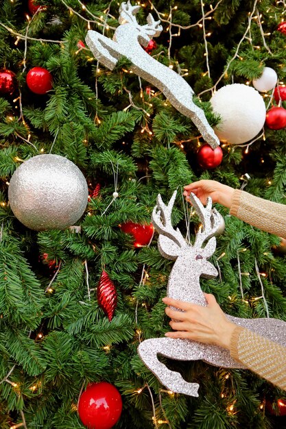 Frau Hände dekorieren Glitter Rentier geformt Ornament auf den Weihnachtsbaum