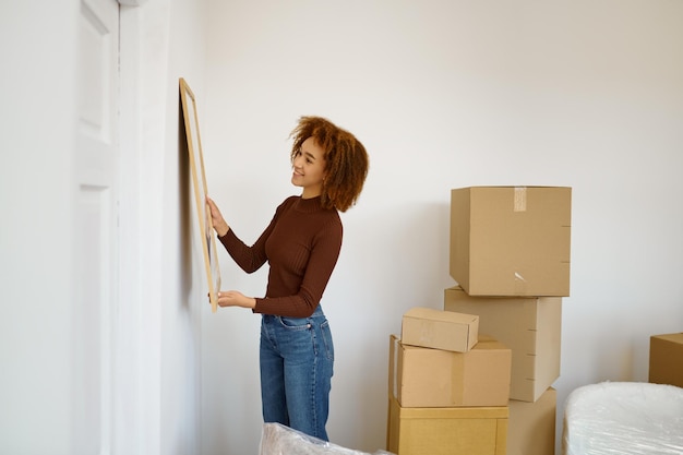 Frau hängt Bild an der Wand