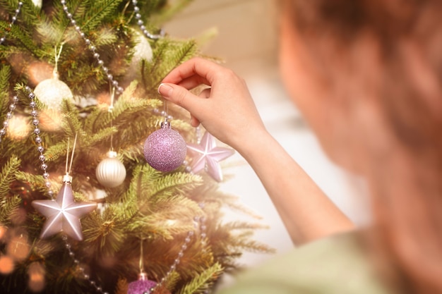 Frau hängt Weihnachtsschmuck an den Baum, Nahaufnahme