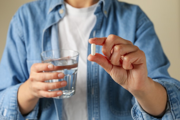 Frau halten Glas Wasser und Pille