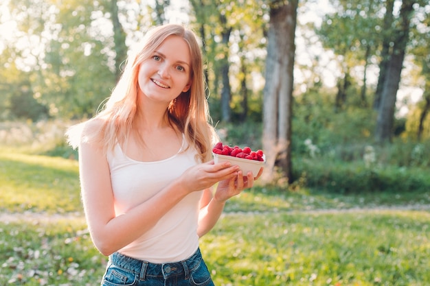 Frau halten Papierbox mit Himbeeren