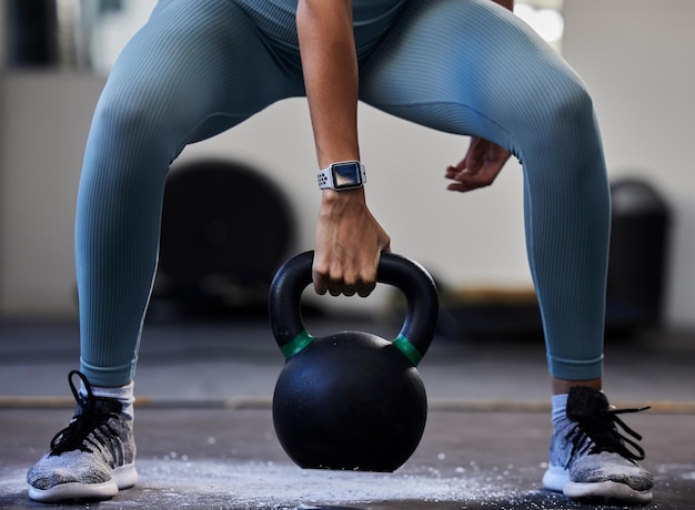 Frau Hand Kettlebell und Turnhalle im Training Fitness oder Muskelaufbau mit Smartwatch Bodybuilder Mädchen Gewichtheben und stark mit Turnschuhen Kreidepulver und Fokus auf Bewegung im Studio