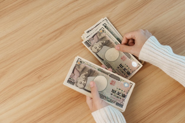 Frau Hand zählen japanische Yen Banknote über Tabellenhintergrund Tausend Yen Geld Japan Bargeld Steuerrezession Wirtschaft Inflation Investitionsfinanzierung Einsparungen Gehalts- und Zahlungskonzepte