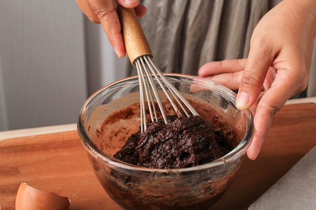 Frau handgemischter Schokoladenteig auf durchsichtiger Schüssel mit Ballonschneebesen Schritt für Schritt Backvorbereitung in der Küche, Herstellung von Schokoladenkuchen oder Brownies