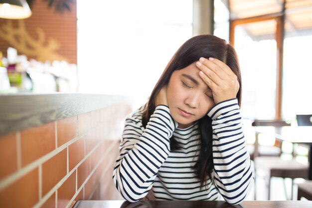 Frau hat Kopfschmerzen im Cafe